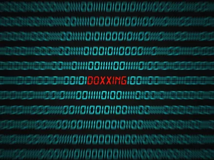 Computer screen with binary code and the word DOXXING in red